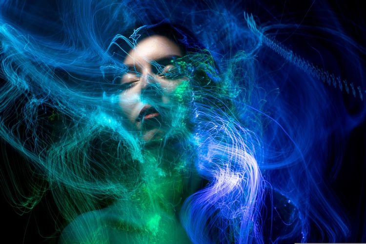 Una donna serena con gli occhi chiusi, avvolta da linee di energia luminose blu e verdi, simbolo di pace interiore ed equilibrio emotivo.